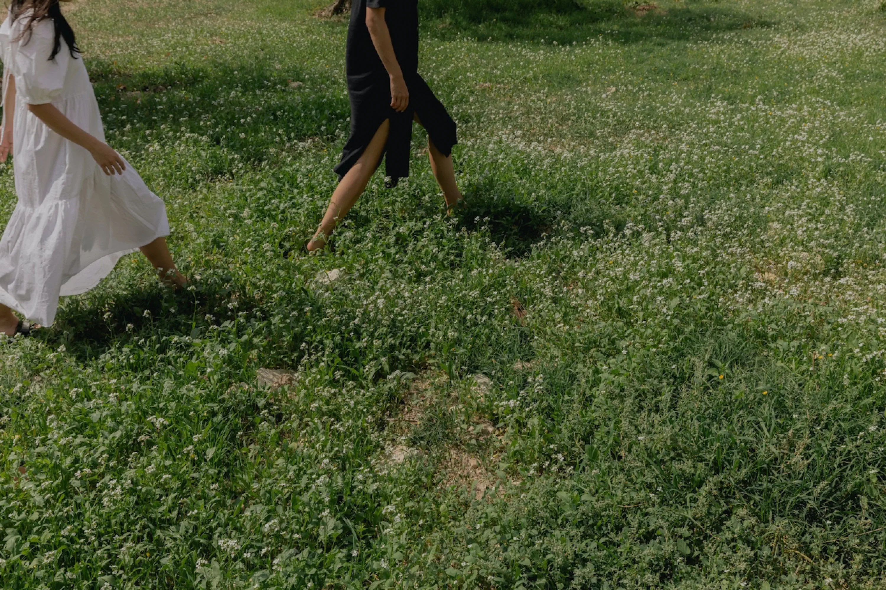 two girls walking outside in a grassy field